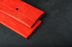 A pair of red genuine leather wallets with rivets on a dark background top view. Genuine leather